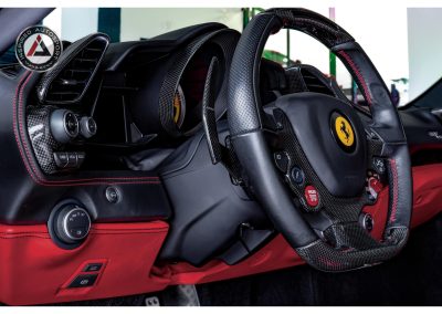 Premium Ferrari racing car interior with carbon fiber steering wheel and red accents for high-performance driving.