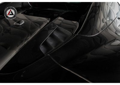 Close-up of a sleek, glossy black high-performance car with aerodynamic details and carbon fiber accents, showcasing luxury and racing-inspired design from Inspired Autosport.