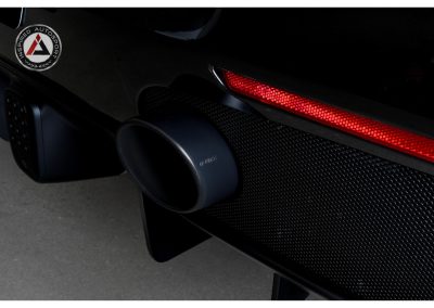 Close-up of high-performance exhaust pipe on a sleek black sports car, emphasizing custom automotive parts and motorsport engineering.