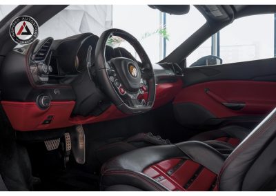 Premium race car interior with racing steering wheel, carbon fiber accents, and customized red and black leather seats for high-performance driving.