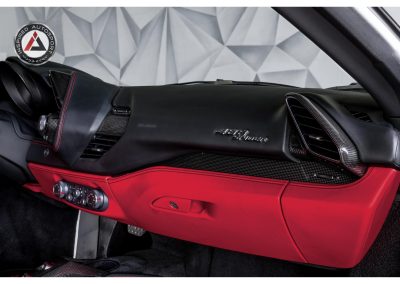 Close-up of luxury Ferrari 488 GTB dashboard featuring custom leather and carbon fiber accents, with "488 GTB" badge, showcasing premium automotive interior design.