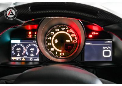 High-resolution interior shot of a Ferrari with illuminated tachometer, speedometer, and digital climate controls, emphasizing luxury sports car performance and automotive technology.