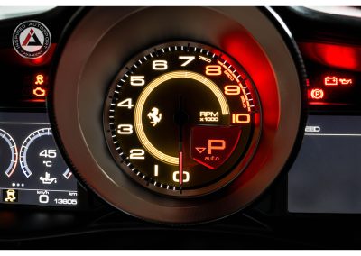 High-quality image of Ferrari RPM tachometer with illuminated indicators, emphasizing precision automotive engineering.