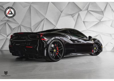 Black Ferrari sports car with aerodynamic design, custom wheels, and high-performance features in a modern showroom.