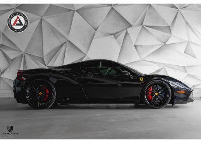 Black Ferrari with red brake calipers parked indoors.