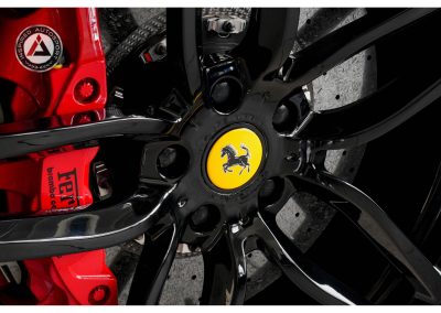 Close-up of Ferrari wheel with black finish, featuring iconic yellow prancing horse logo at center, showcasing high-performance design and racing aesthetics.