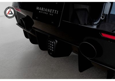 Close-up of performance racing car exhaust and diffuser with custom branding and aerodynamic features for high-speed motorsport.