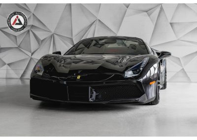 High-resolution image of a sleek, black Ferrari supercar inside a modern showroom with geometric wall design, showcasing premium automotive engineering and design.
