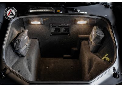 Close-up of a sleek car trunk interior with storage pouches and safety equipment, highlighting automotive customization and racing accessories.