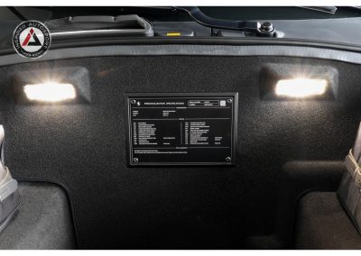 Close-up of a customized supercar dashboard featuring a personalized specification plaque and LED lighting, emphasizing luxury and automotive excellence.